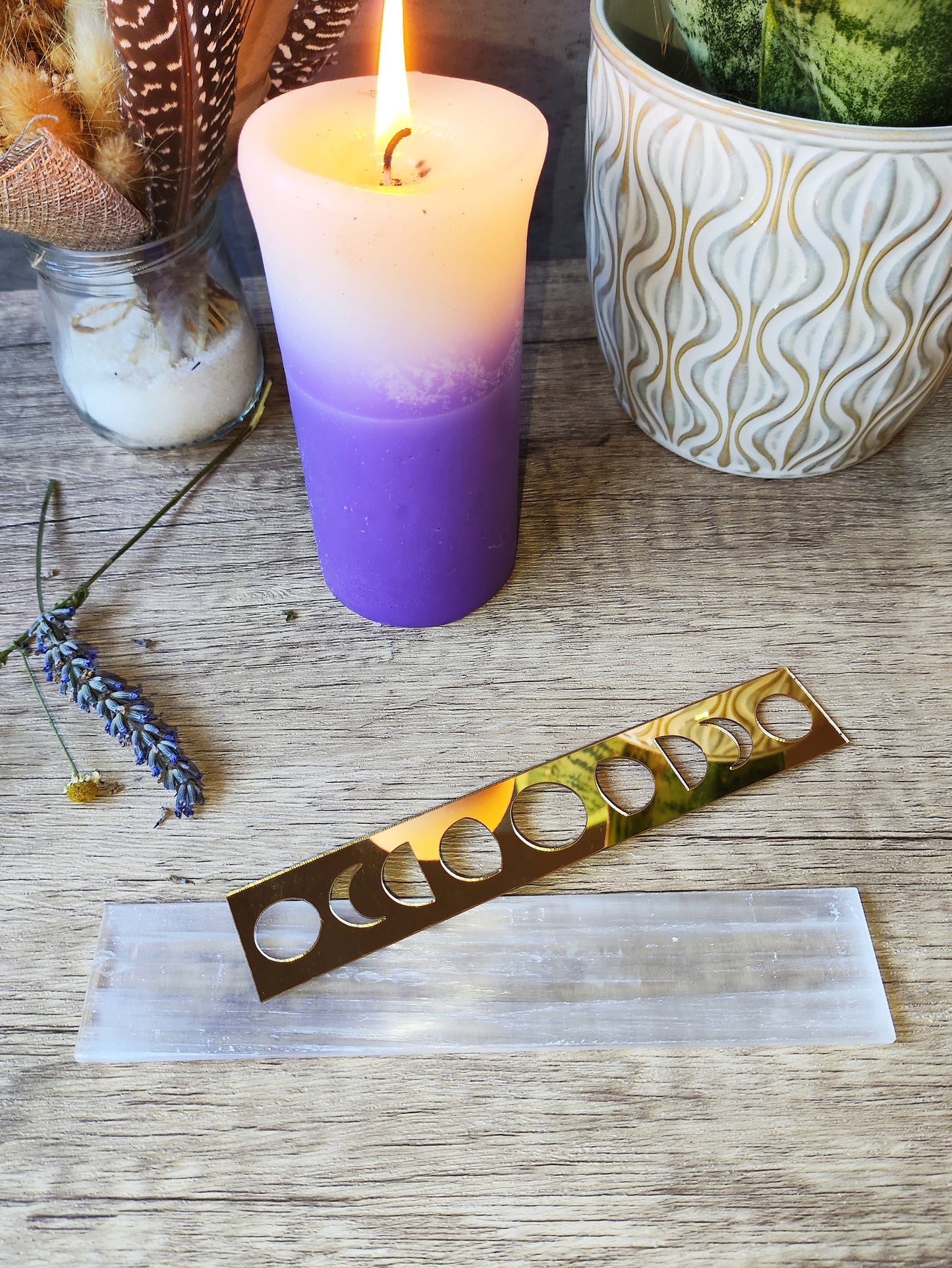 placa rectangular de selenita con fases lunares doradas montada junto a vela encendida, lavanda y decoración esotérica.