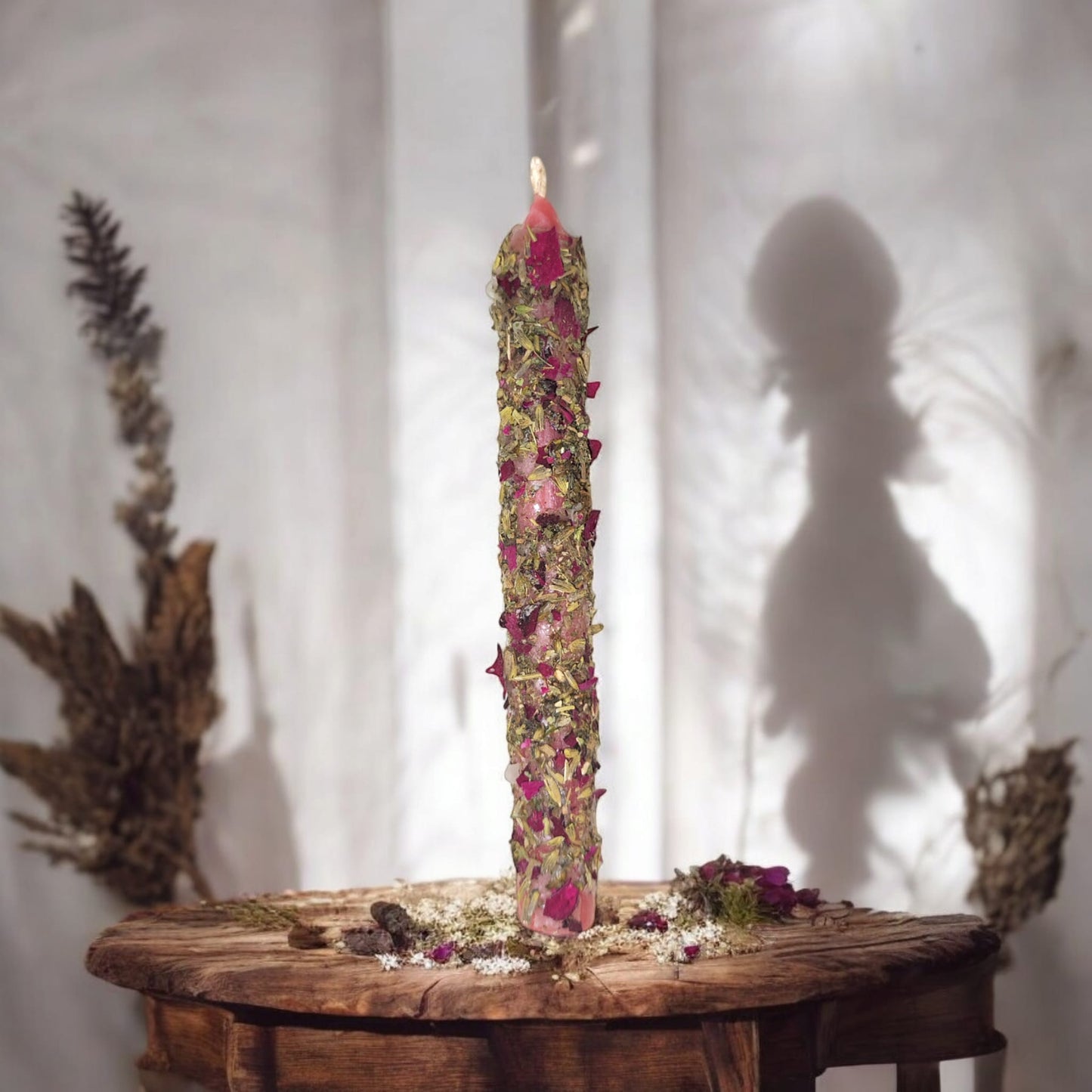 vela ritualizada decorada con hierbas, para equilibrio emocional y armonía en mesa y sombras