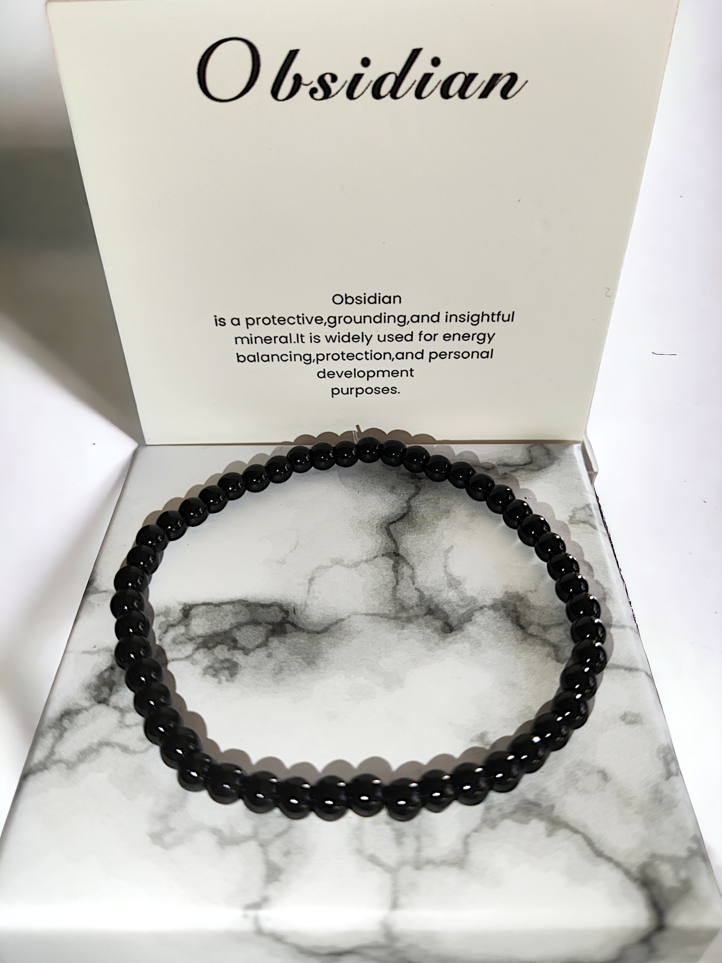 pulsera de cuentas de obsidiana pulida sobre fondo blanco