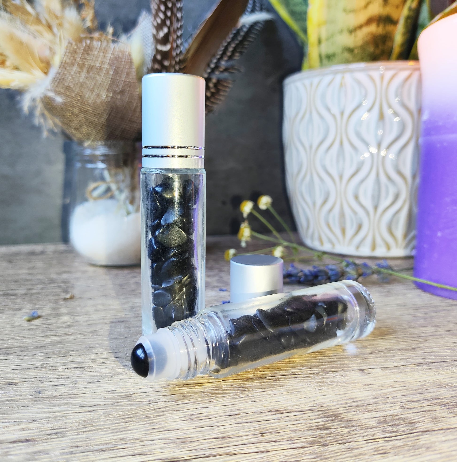 Frasco roll-on de obsidiana negra, con decoración mística y fondo esotérico.

