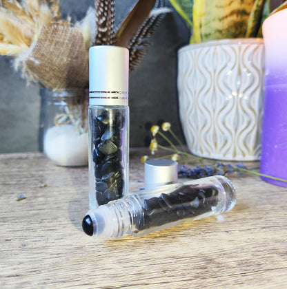 Frasco roll-on de obsidiana negra, con decoración mística y fondo esotérico.

