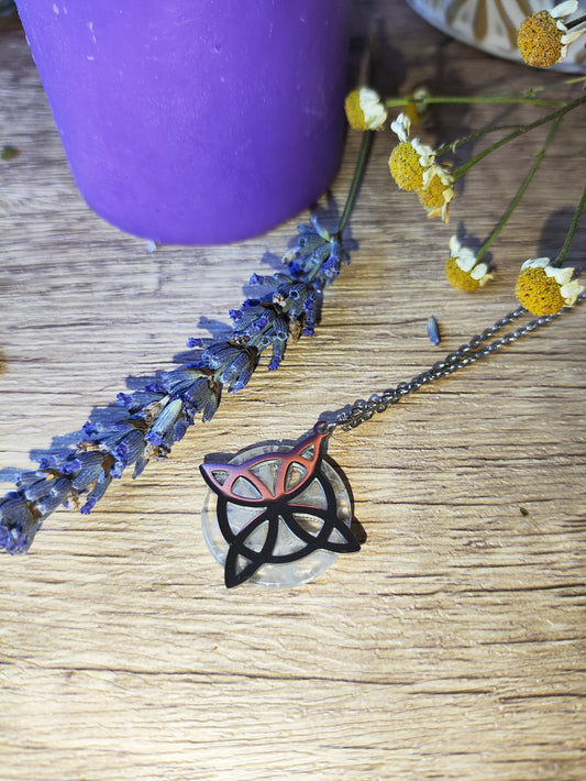 Colgante nudo de brujas con cuarzo cristal sobre fondo de madera, acompañado de flores secas y decoración mágica.