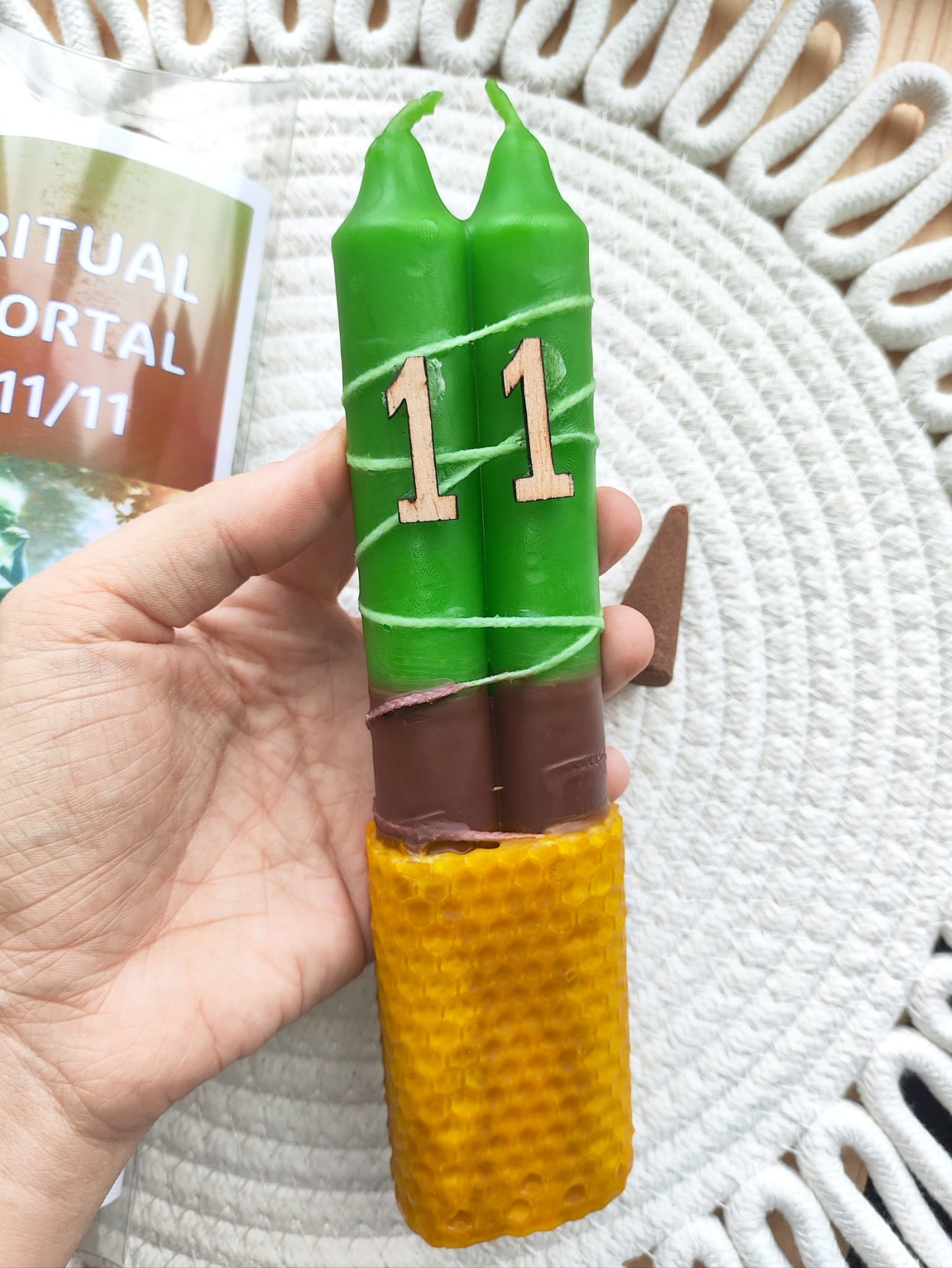 Ritual Portal 11:11 con vela doble verde y base de cera de abeja natural – apertura energética y manifestación en fondo claro sujeto por una mano