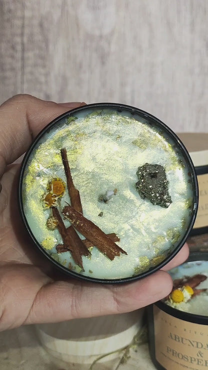 Vela ritualizada Abundancia y Prosperidad con pirita, brillo dorado y hierbas mágicas; movimiento para apreciar los detalles.