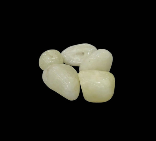 Rodado de cuarzo con azufre natural de tono amarillo suave sobre fondo negro, piedra esotérica de purificación energética